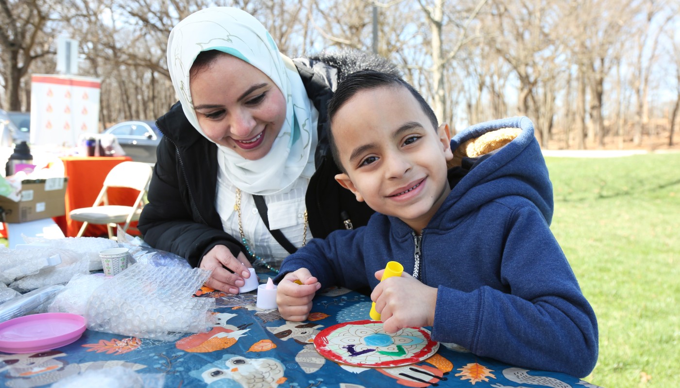 A family working on arts and crafts at a table outdoors.