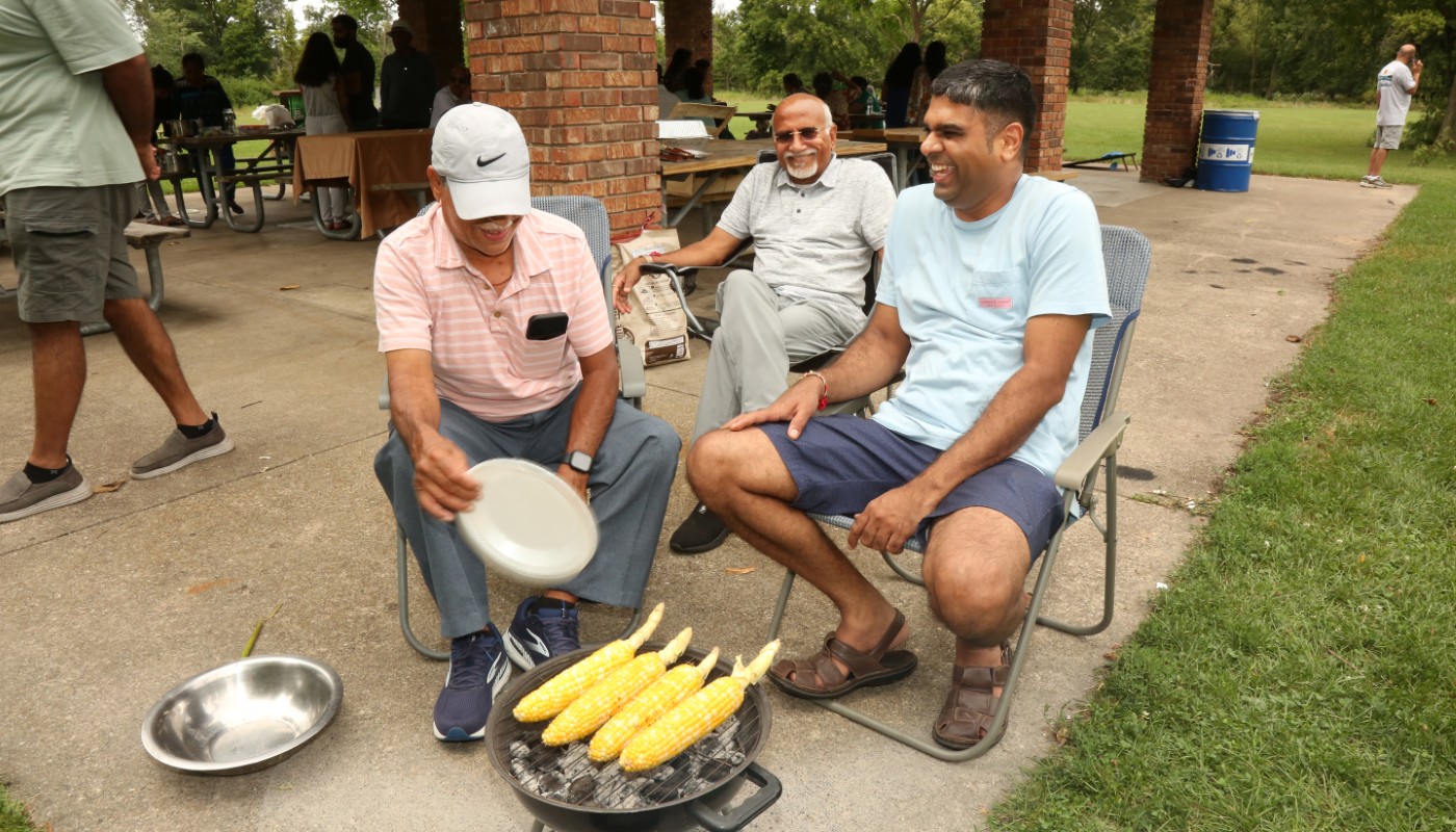 A group of people enjoying their time at an outdoor picnic pavilion.