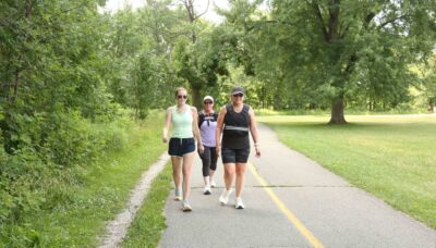 A group walking on a paved trail in a forested area.