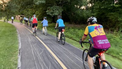 A group of people bicycling on a paved trail at dusk.