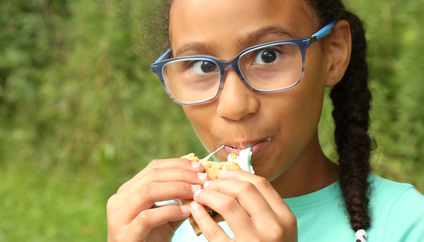 A child eating food near a campfire.