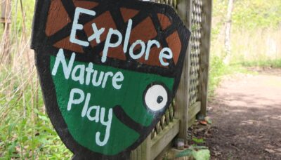 Outdoor signage highlighting a nature play area.
