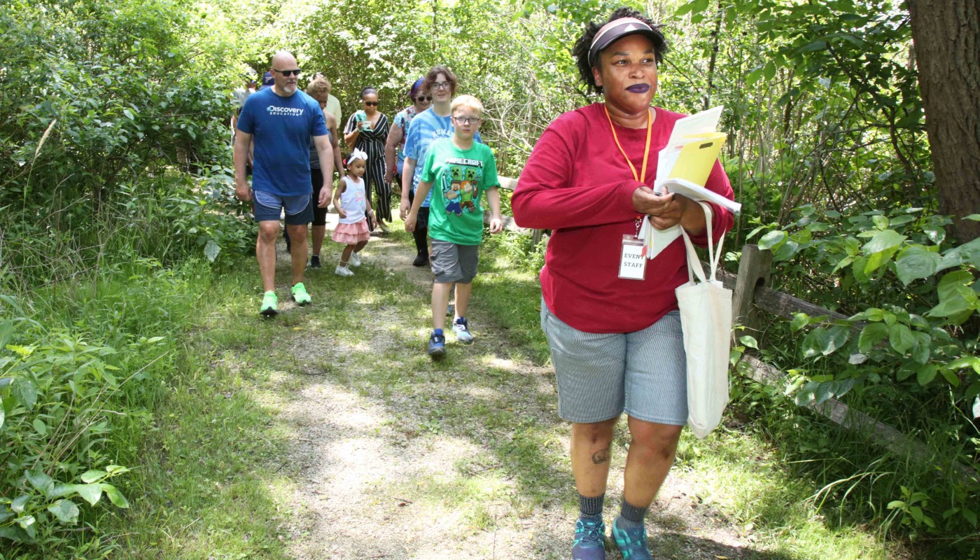 A group walking along an outdoor unpaved trail.