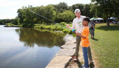 A group of people near a body of water with a fishing pole.