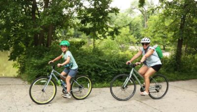 An adult and child biking together outdoors.