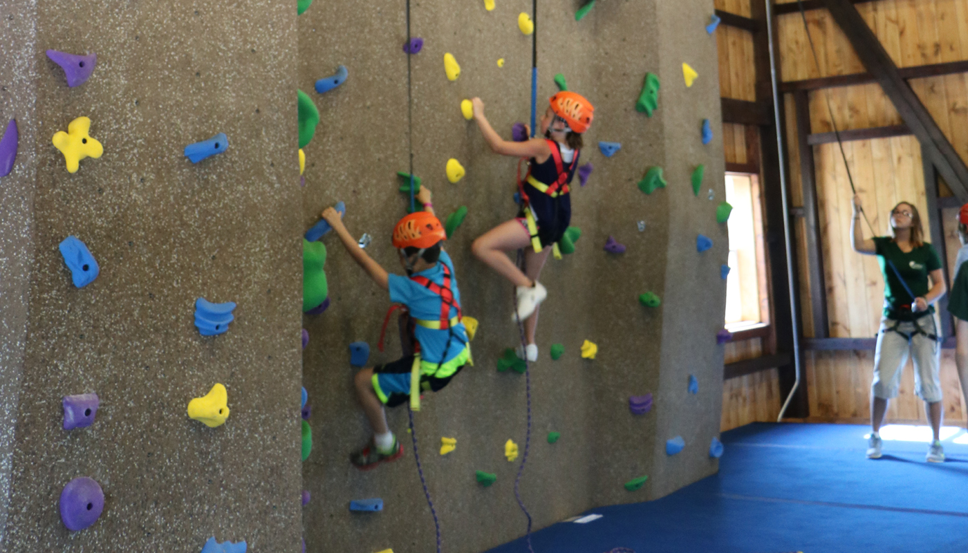 a couple of kids climbing a rock climbing wall