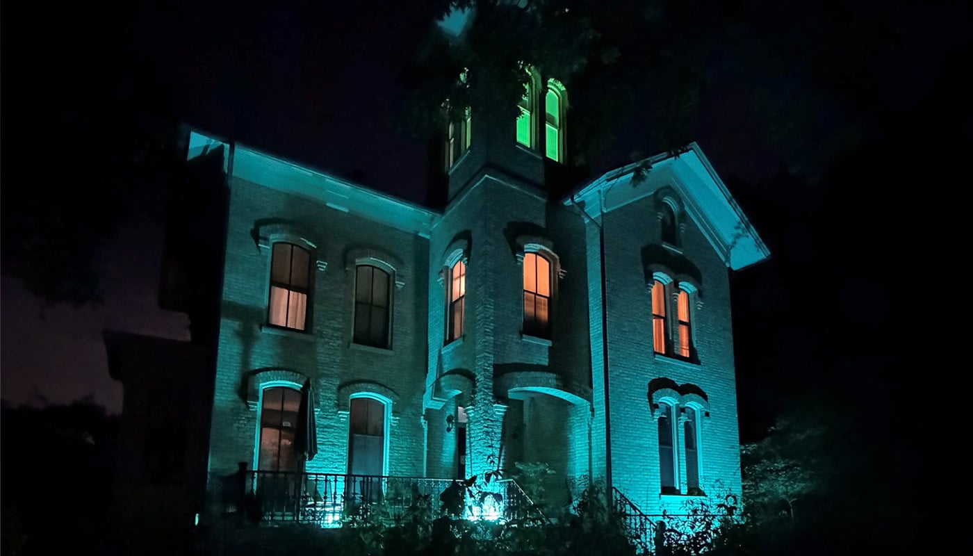 A photo of Trailside Museum at night, illuminated with spooky lighting for the Halloween season.