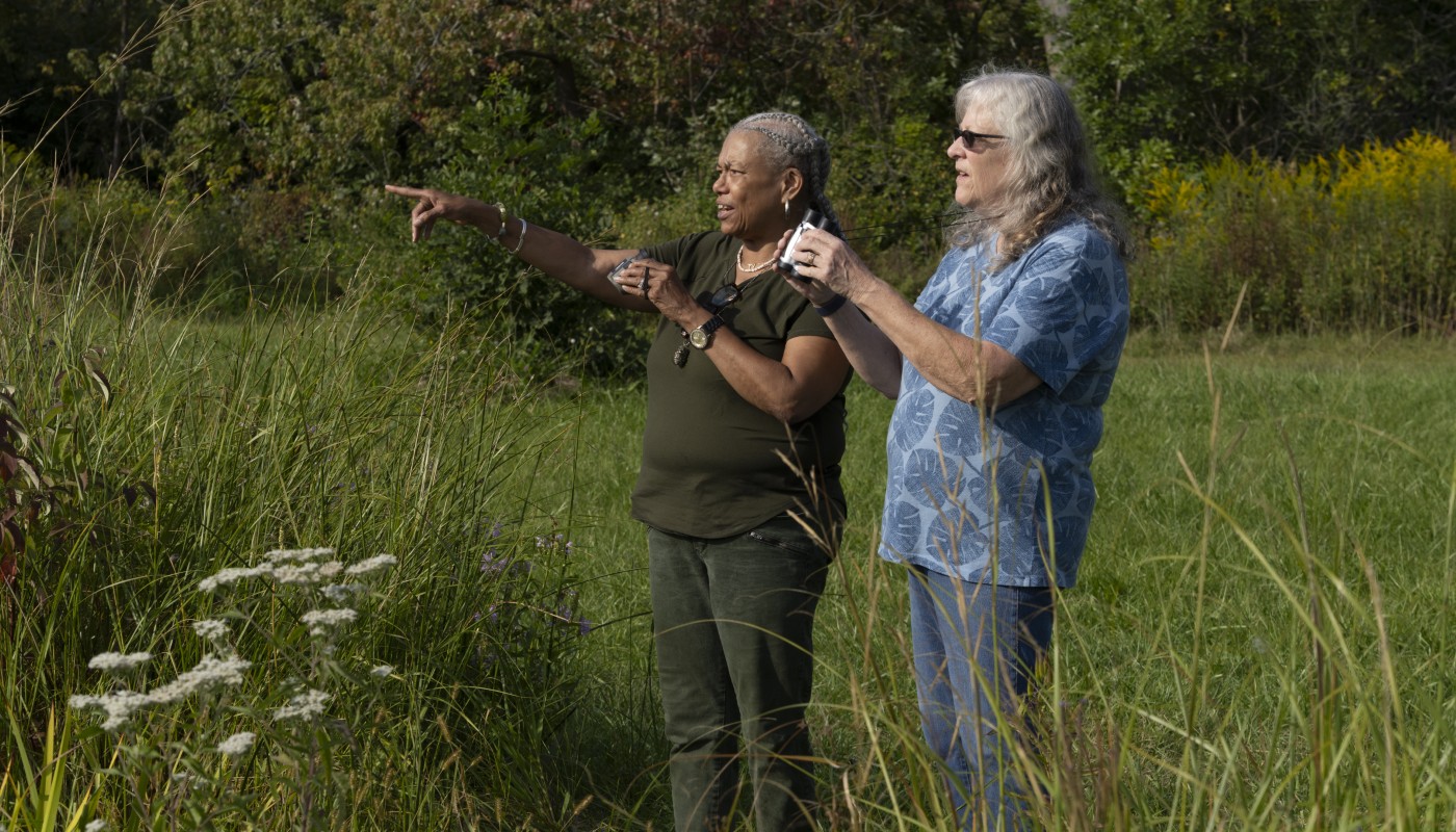 Two people birding with binoculars in hand.