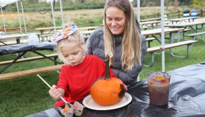 A mother and child painting a pumpkin.