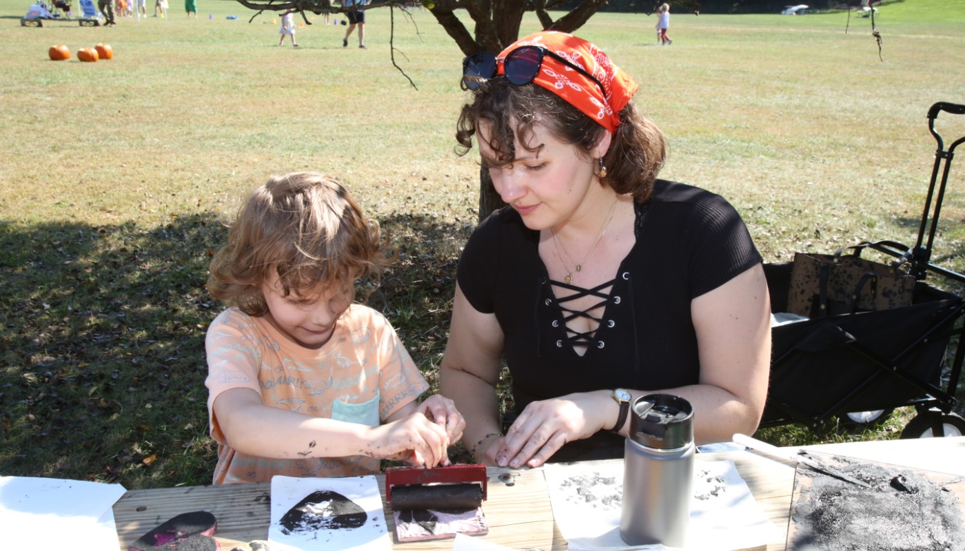 An adult and child creating art in an outdoor setting.