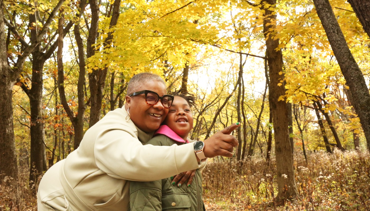An adult and child gazing upon the fall colors in a forest.
