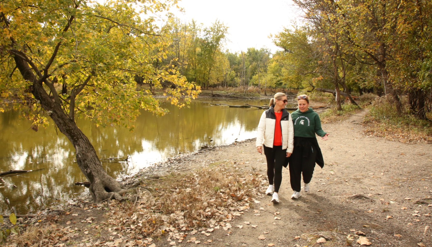 A group of people hiking in a forest with a backdrop of fall colors.